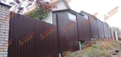 Забор из профнастила на склоне на винтовой свае Выборг